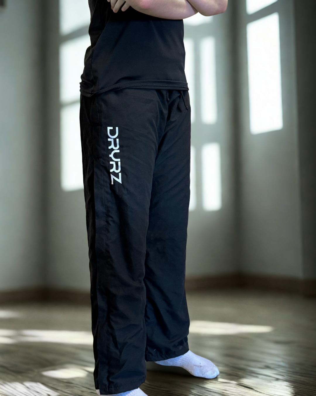 Model standing arms crossed in DRYRZ black BambooLayer bamboo-lined thermal joggers, emphasizing soft-touch comfort and post-workout heat retention. Ideal for cold weather recovery.
